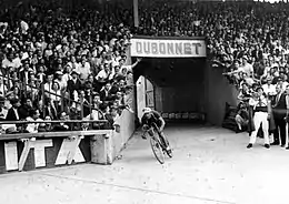 A cyclist entering a crowded stadium.