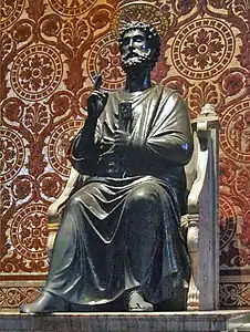 Peter is shown as a bearded man in draped garment like a toga. He is seated on a chair made of marble, and has his right hand raised in a gesture of blessing while in his left hand he holds two large keys. Behind the statue, the wall is patterned in mosaic to resemble red and gold brocade cloth.