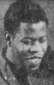 A young Black man, smiling, with a violin under his chin