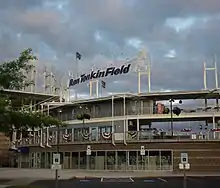 Ron Tonkin Field has a main grandstand built of concrete with a metal roof suspended by cable attached to several towers. Backside of grandstand with park signage shown.