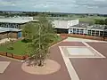 View from main block of Quad with Sports hall, Sixth Form Centre and Humanities blocks with sports fields behind.