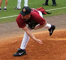 right-handed pitcher wearing a red Astros uniform throws a baseball from a pitching mound.