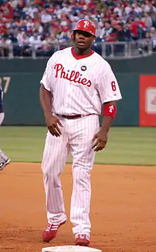 A man in a white baseball uniform and red cap