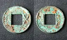 Two circular bronze coins with square holes in the center which have been corroded over time with a green color