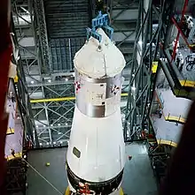 A conical spacecraft is maneuvered atop a rocket