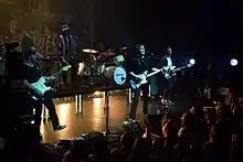 Sam Fender and his backing band members onstage, under a dim light