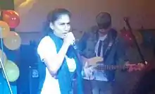 Samira Saraya rapping onstage with System Ali band member playing bass guitar in the background