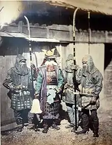 1870 photograph of samurai and retainers wearing mail armour and holding naginata.