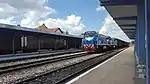 A freight train passing through the station, headed by two TGM8 locomotives