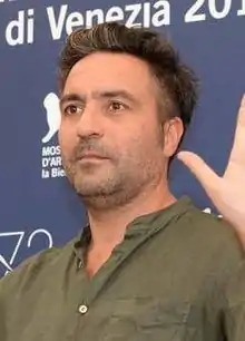 Saverio Costanzo facing right of the camera, waving at an audience