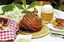 A table with a platter of meat, a glass of beer, and other foods.