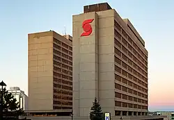 Two rectilinear, concrete high-rise buildings. The building on the right, Duke Tower, has a large red Scotiabank logo on the concrete façade facing the photographer.