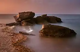 Rocks at sea illuminated by the gas flares of oil refineries