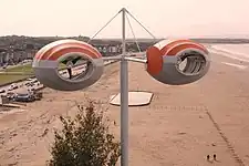 An artwork consisting of dual wind turbines overlooking a seafront.