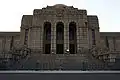 2007 image of the central entrance as realized, showing rustication of the lower courses, dentilation, glyphs, engaged pilasters in the wings, and stained glass windows