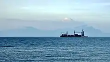 A container ship, Selatan Damai, anchored off Dili, East Timor, in 2018 with Atauro in the background