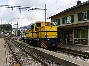 Yellow locomotive in front of two-story building