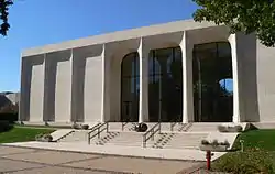 Two-story stone-clad building; middle third glass-walled; wide steps leading up to it