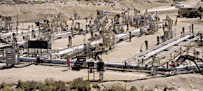 A photograph of Shell Oil's experimental in situ shale oil extraction facility in the Piceance Basin of northwestern Colorado. In the center of the photo, a number of oil recovery pipes lie on the ground. Several oil pumps are visible in the background.