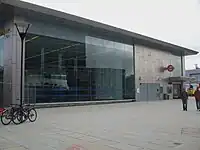 metal and glass building with open front and escalators on Shepherd's Bush Green