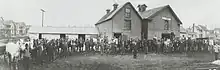 Photo of man in suit in front of horses and barn