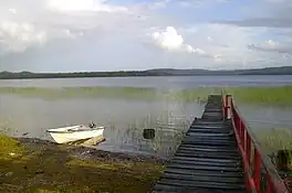 Photograph of the lake with a small boat and jetty in the foreground