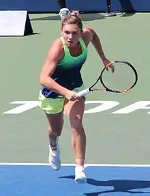 Halep running towards the left side of the net from just inside the baseline near the center of the court