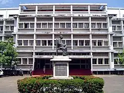 Large white building with a statue of a seated figure in front