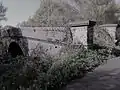 A now-defunct railway bridge to the west of the village.