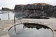 Cold plunge pool with lagoon and rocks in background