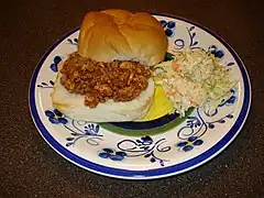 A sloppy joe sandwich with a side dish of coleslaw