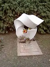 Grave with elaborate carved headstone and plain slab with inscription. There are fresh flowers on the grave.