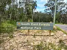 Photograph of an official sign for the national park at one of its road boundaries using the pluralised word, "forests".