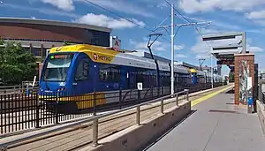 A light rail car at a station in front of U.S. Bank Stadium.