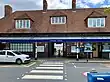 A brown-bricked building with four brown-bricked chimneys and a rectangular, dark blue sign reading "STANMORE STATION" in white letters