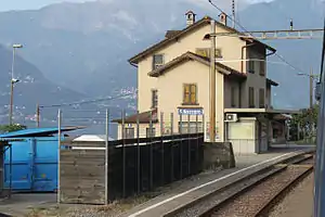 Three-story building with gabled roof next to double-track railway line