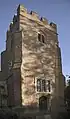 St Mary's brick-built, early 16th-century tower (with later crenellation), diagonal buttresses and square-headed three pane window above wooden door