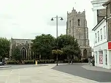 A flint church seen from the north with a battlemented tower to the right