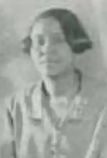 A young Black woman with short hair, wearing a light-colored blouse