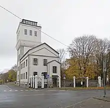 A tall white building with a four-story tower at the back and a two-story building at the front