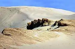 Rocks in front of a large sand dune on a sunny day