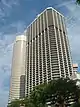 Ground-level view of 50-storey box-like building with dark, receded windows and cut-off, diagonal corners