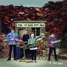 A rock band made up of children performing in front of a pile of junk