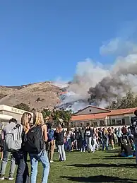 Onlookers watch plumes of smoke coming from the hill behind the school.