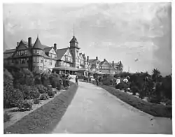 A path leads to a grand hotel in High Victorian style on a hill