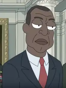 A black man wearing a suit. He has his eyes narrowed with a frown.