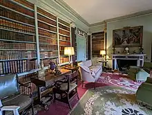 A library decorated with 18th century art and furniture, with books lining the walls