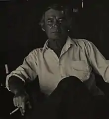 A man sitting, smoking a cigarette.