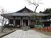 Wooden building with white walls, a raised floor with railed veranda and a hip-and-gable roof.