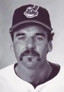 A man in a light baseball jersey and dark cap